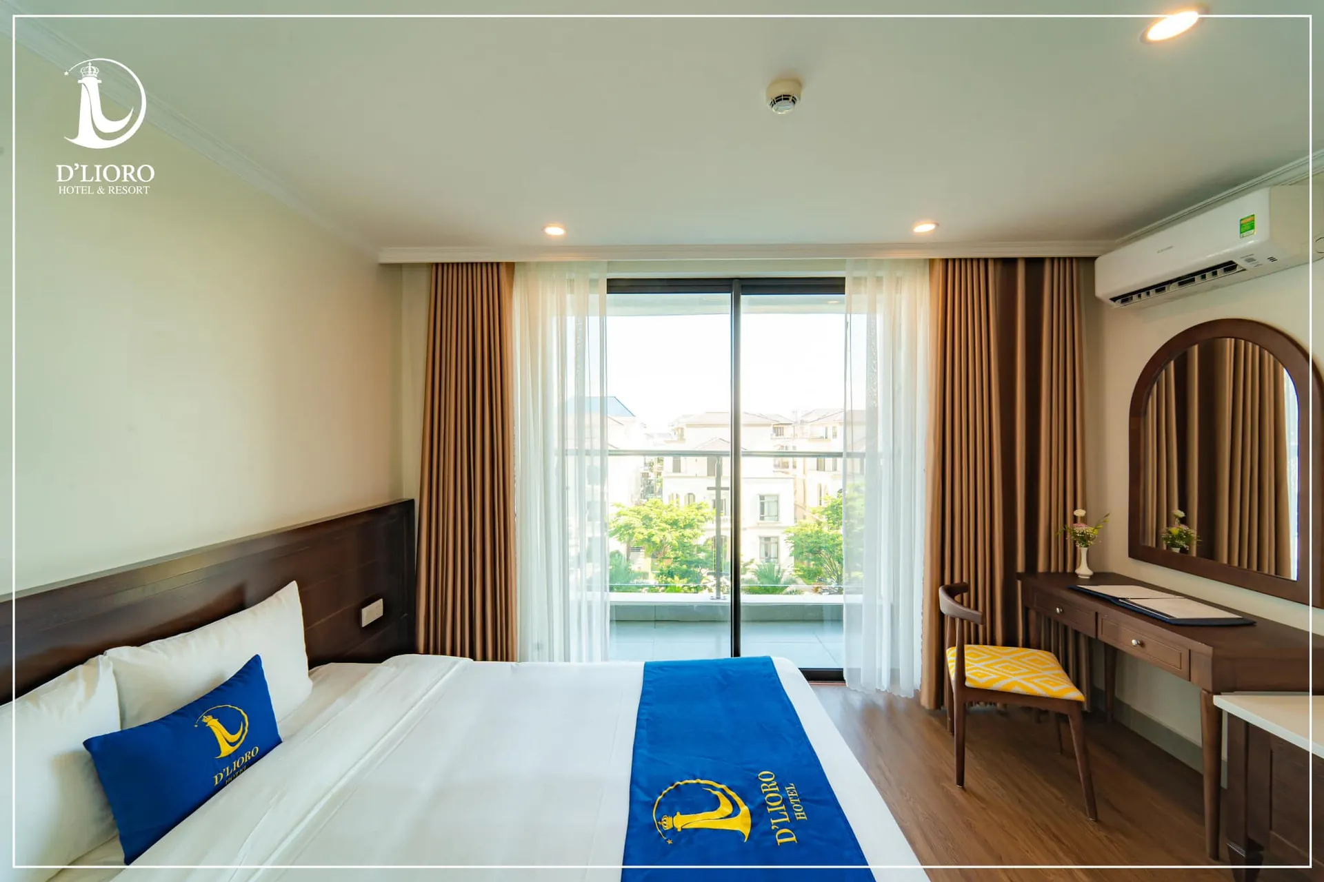 Phòng ngủ D'Lioro Hotel & Resort với đầu giường và bàn trang điểm gỗ